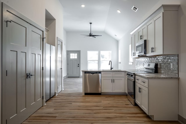 kitchen featuring visible vents, a sink, appliances with stainless steel finishes, a peninsula, and ceiling fan