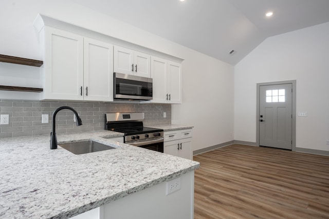 kitchen with lofted ceiling, open shelves, a sink, stainless steel appliances, and white cabinetry