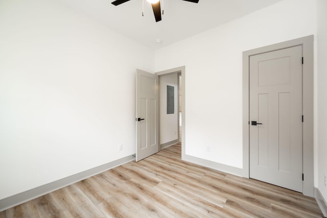 unfurnished bedroom with electric panel, light wood-style floors, baseboards, and ceiling fan