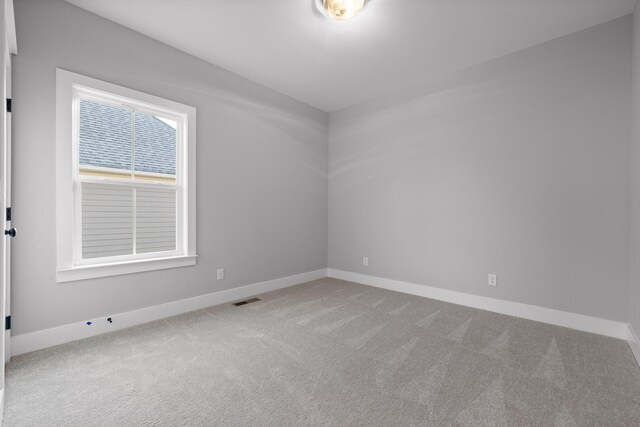 carpeted spare room with visible vents and baseboards