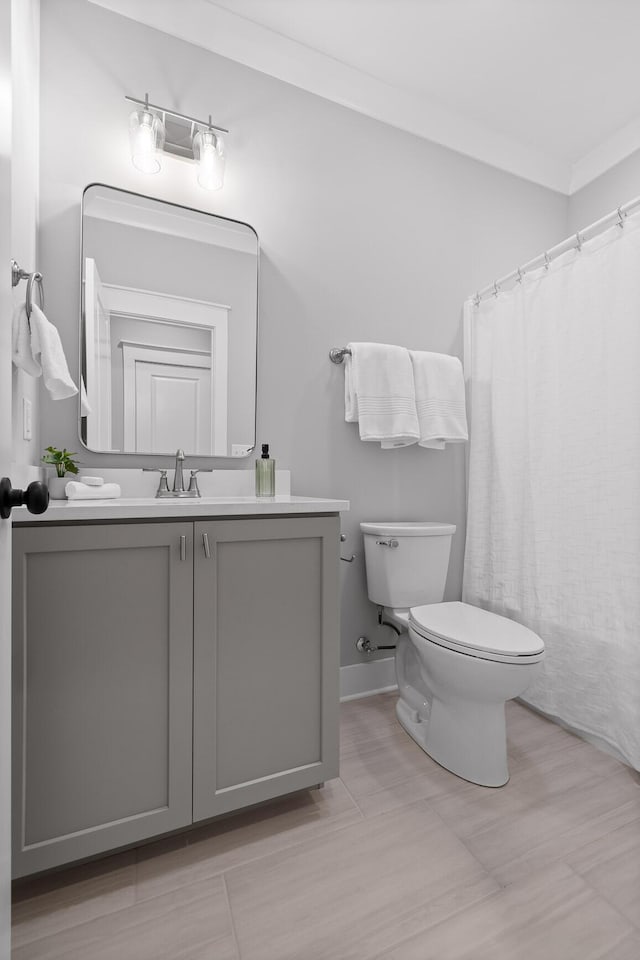 bathroom with toilet, ornamental molding, and vanity