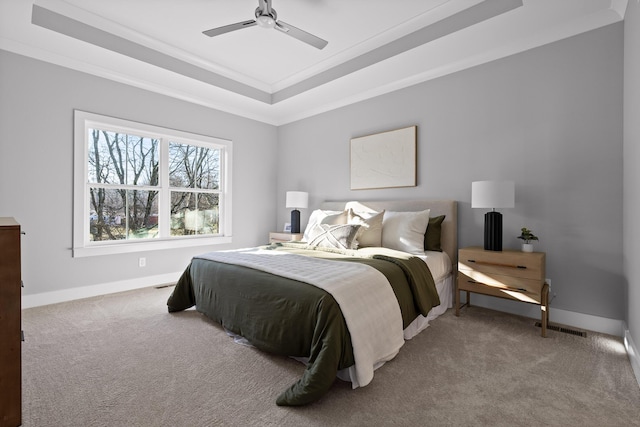 carpeted bedroom with a ceiling fan, a raised ceiling, crown molding, and baseboards