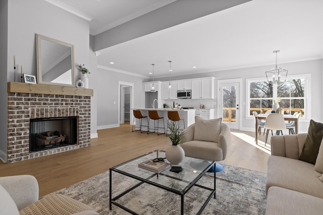 living area featuring baseboards, ornamental molding, a brick fireplace, and light wood-style floors