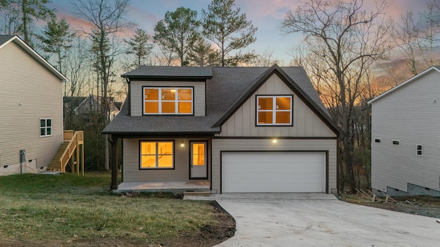 view of front facade featuring a garage, a yard, roof with shingles, and board and batten siding