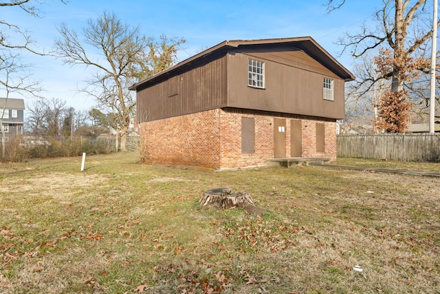 view of property exterior featuring brick siding, a lawn, and fence