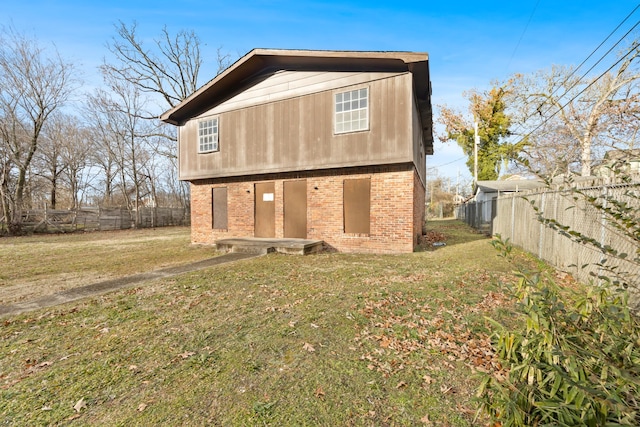 rear view of house with a yard, brick siding, and fence