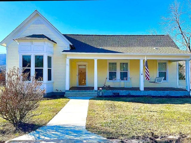 view of front of home with a porch, a front yard, and a shingled roof