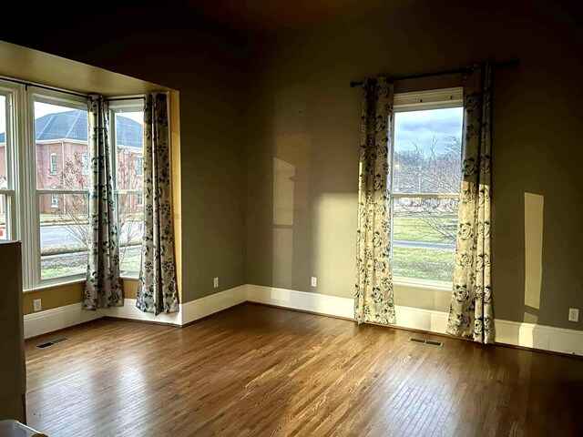 unfurnished room with visible vents, baseboards, and wood finished floors