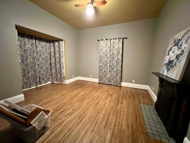 living area featuring ceiling fan, baseboards, and wood finished floors