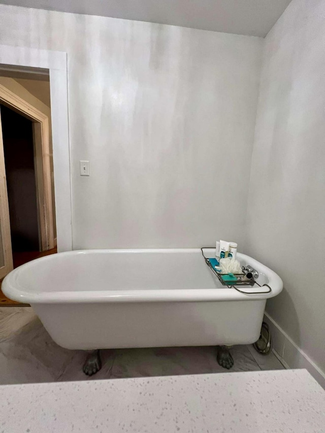 bathroom with a freestanding tub, baseboards, and tile patterned floors