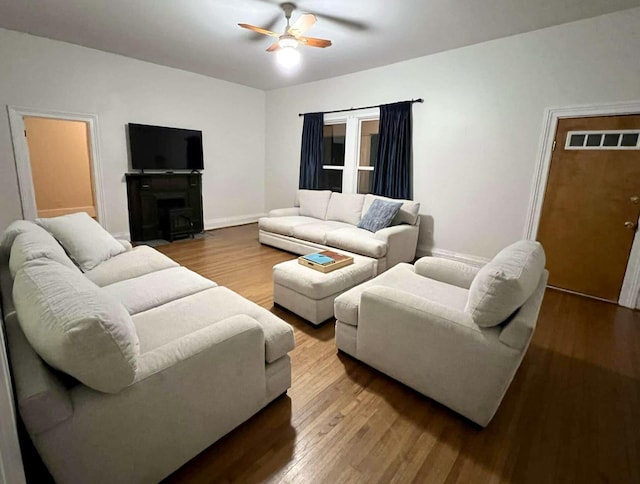 living area with ceiling fan, a fireplace, visible vents, and wood finished floors