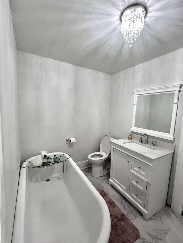 bathroom with toilet, marble finish floor, a freestanding bath, vanity, and a chandelier