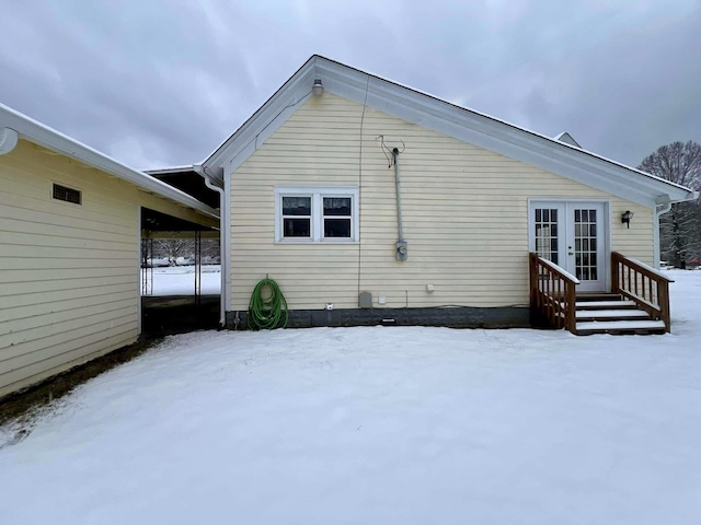 snow covered property with a carport and french doors