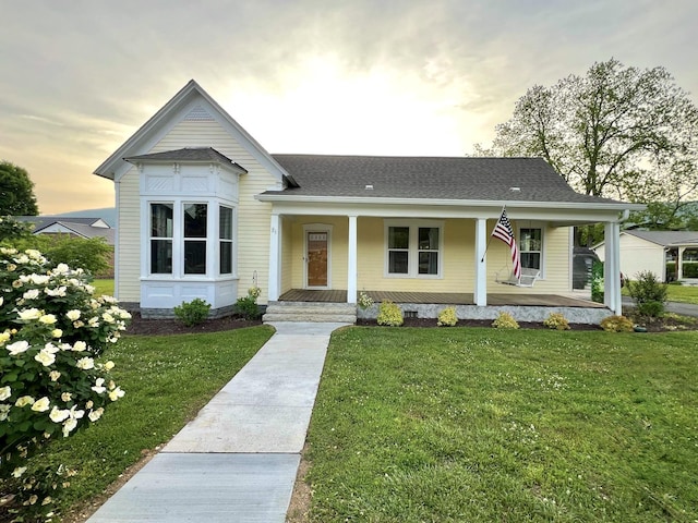 view of front of property with a lawn, a porch, and roof with shingles