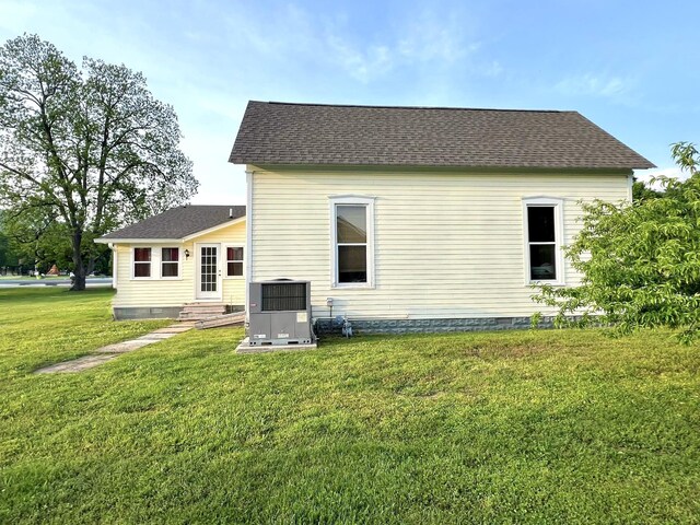 back of house featuring a yard, crawl space, and roof with shingles