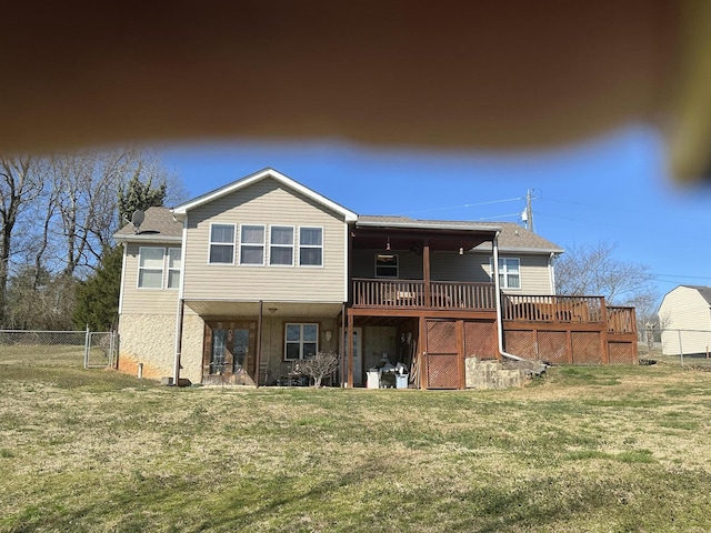 rear view of property featuring a yard, a wooden deck, and fence