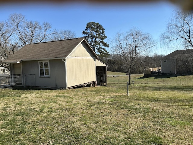 exterior space featuring a shingled roof, an outbuilding, and a lawn