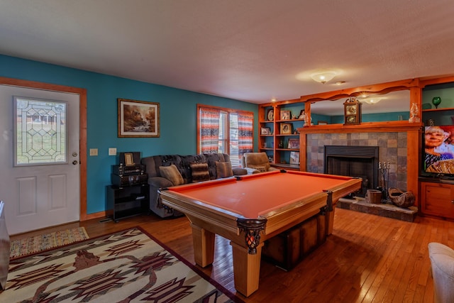 recreation room with built in features, a fireplace, hardwood / wood-style floors, and pool table