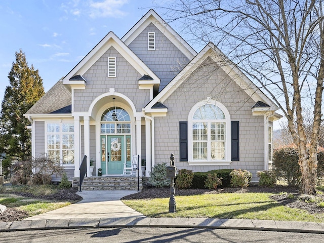 view of front of property with a shingled roof and a front yard