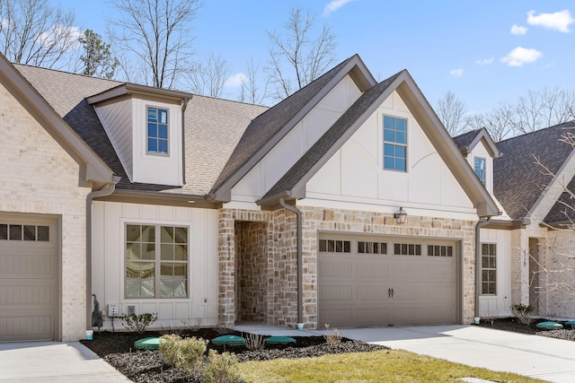 view of front facade featuring driveway, a garage, a shingled roof, stone siding, and board and batten siding