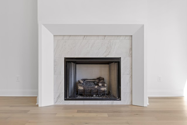 details with baseboards, a tiled fireplace, and wood finished floors