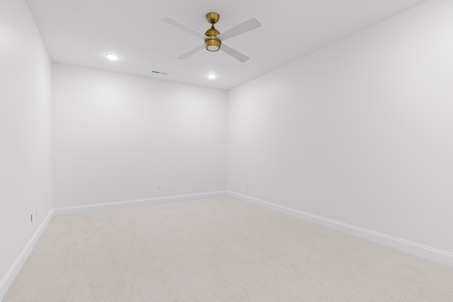 carpeted spare room with visible vents, baseboards, and a ceiling fan