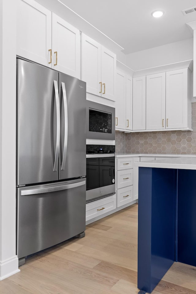 kitchen with light wood finished floors, visible vents, appliances with stainless steel finishes, light countertops, and white cabinetry