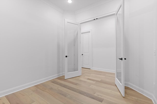 interior space with light wood-type flooring, crown molding, and baseboards