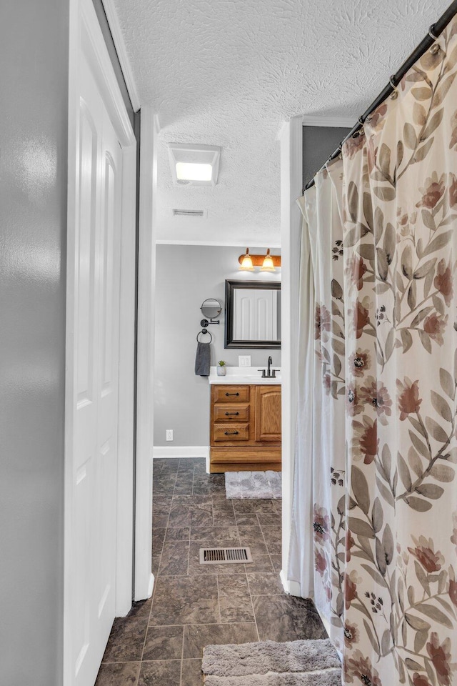 bathroom featuring visible vents, a shower with shower curtain, vanity, a textured ceiling, and baseboards