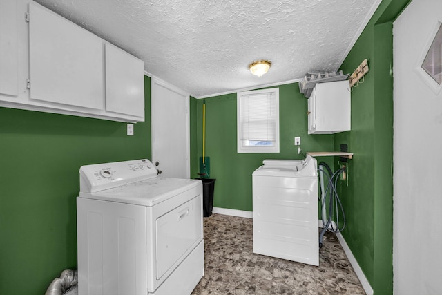 laundry area featuring cabinet space, baseboards, separate washer and dryer, and a textured ceiling