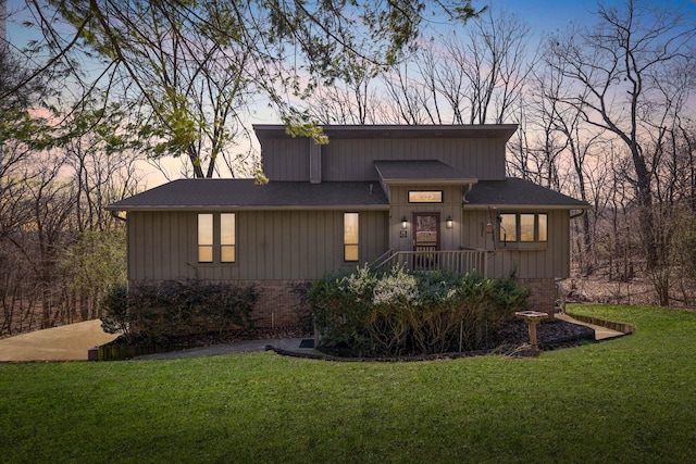 view of front of home featuring a shingled roof, a lawn, and brick siding