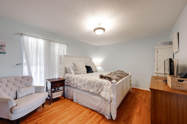 bedroom featuring light wood-style floors, multiple windows, and a textured ceiling