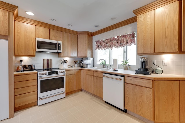 kitchen featuring white appliances, decorative backsplash, light countertops, light brown cabinets, and a sink