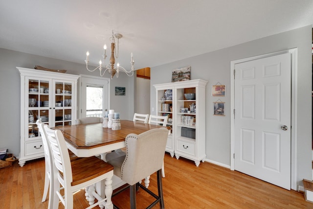 dining area with light wood finished floors and a chandelier