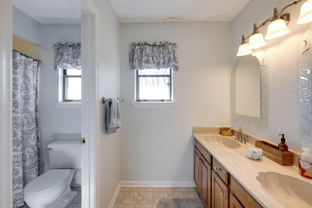 full bath featuring double vanity, baseboards, toilet, and a sink