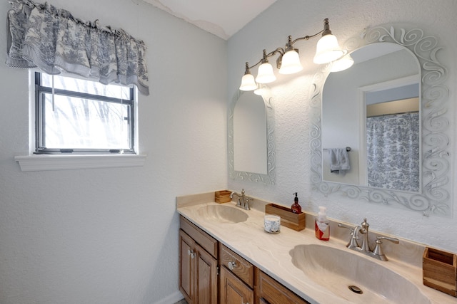 bathroom with a textured wall, double vanity, and a sink