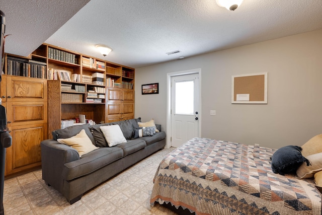 bedroom with visible vents, a textured ceiling, and light floors