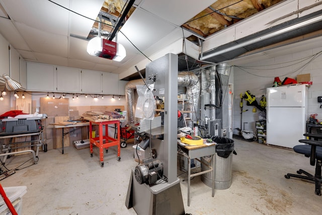 garage with a workshop area, freestanding refrigerator, and a garage door opener