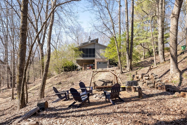 view of yard featuring an outdoor fire pit, an attached garage, and a sunroom