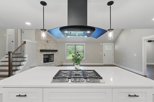 kitchen with white cabinets, stainless steel gas stovetop, open floor plan, a fireplace, and island exhaust hood