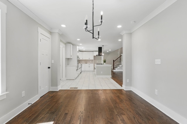 unfurnished living room featuring recessed lighting, stairs, baseboards, light wood-type flooring, and a notable chandelier