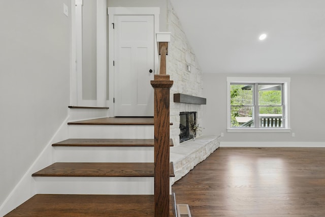 stairway with lofted ceiling, visible vents, baseboards, a fireplace, and wood finished floors
