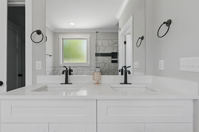 full bath featuring double vanity, crown molding, tiled shower, and a sink