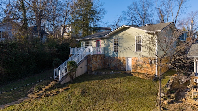 rear view of property featuring stairs, a yard, and stone siding