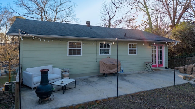 rear view of property with roof with shingles and a patio area