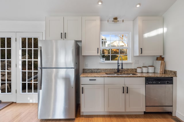 kitchen featuring white cabinetry, appliances with stainless steel finishes, dark stone counters, and a sink