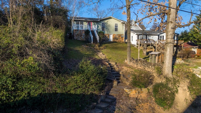 exterior space with stone siding, a front lawn, and stairway