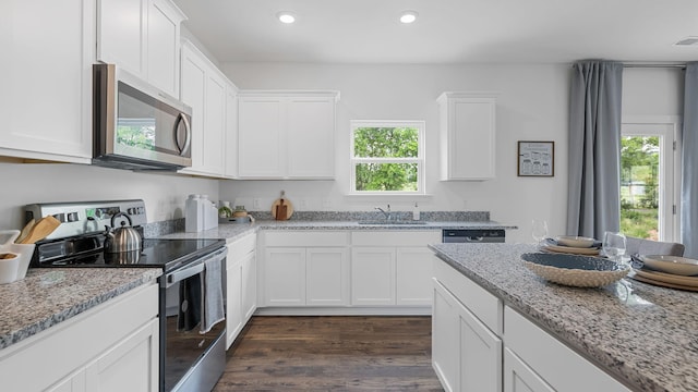 kitchen featuring stainless steel appliances, a sink, white cabinetry, and light stone countertops