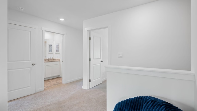 hallway with recessed lighting, light carpet, and baseboards