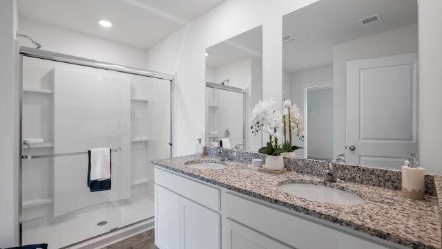 bathroom with double vanity, a sink, visible vents, and a shower stall